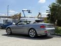 A silver 2004 BMW 6-Series convertible with a soft top and distinctive alloy wheels parked with the roof down