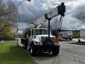 A white 2008 International 7500 truck with a crane mounted on the bed parked on a street