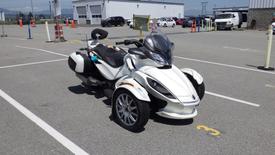 A white 2013 Can-Am Spyder equipped with three wheels a comfortable seat and a large windshield designed for a unique riding experience