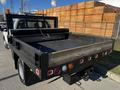 A 2011 Ford F-350 SD with a flatbed and rear-mounted lights showing a black metal frame with mesh and a roll-up tarp at the back