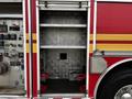 An open storage compartment on a 2009 Spartan Gladiator fire truck with metal shelves and no equipment visible inside