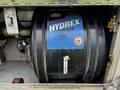 A blue and black drum labeled HYDRX MV22 hydraulic oil inside a compartment of a vehicle