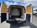 A white 2009 Chevrolet Express van with its back doors open revealing an empty cargo area and yellow insulation lining the interior walls