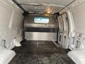 Interior view of a 2011 Ford Econoline van with a plain cargo area featuring gray rubber flooring and a metal partition behind the front seats