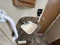 A small sink with a faucet is mounted on a countertop inside a recreational vehicle with a grab bar attached to the wall nearby