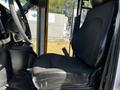 A 2019 Chevrolet Express driver's seat with a black fabric cover and armrest situated next to the steering wheel and dashboard