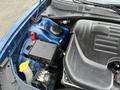 Close-up view of the engine bay of a 2022 Dodge Charger showing the battery and various components including a coolant reservoir and part of the engine cover