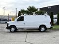 A white 2008 Ford Econoline van with a ladder rack on the roof parked on a concrete surface