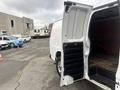 A white 2022 GMC Savana van with an open side door revealing a wooden interior and black rubber floor mat