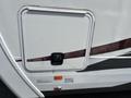 Side compartment door of a 2013 Outdoor Wind River travel trailer with a maroon and silver design and a locking mechanism