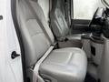 Interior of a 2019 Ford Econoline with two gray front seats and a central console featuring cup holders