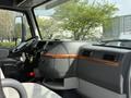 Interior view of a 2012 Volvo VNL showing the dashboard and controls with wooden trim and storage compartments