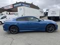 A blue 2022 Dodge Charger with a sleek design and black rims is parked with its side profile facing the viewer
