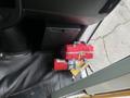 A red first aid kit and a fire extinguisher are placed on the floor of a vehicle next to the driver's seat