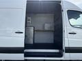2017 Mercedes-Benz Sprinter with an open side door revealing a spacious interior featuring shelves and a wooden counter