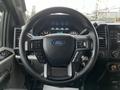 Close-up of the steering wheel and dashboard of a 2016 Ford F-150 featuring the Ford logo and various control buttons
