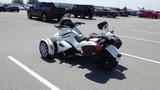 A white 2013 Can-Am Spyder three-wheeled motorcycle with a sporty design and a windshield parked in a lot