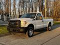 A white 2012 Ford F-250 pickup truck parked on a road featuring a single cab and black front grille with round headlights and rugged tires