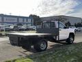 A white 2017 Chevrolet Silverado 3500HD flatbed truck is parked with a metal mesh back and a long flatbed designed for carrying large loads