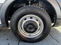 A close-up of a silver wheel with a black tire featuring deep treads and a circular pattern on the rim of a 2018 Ford Transit