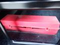 A red plastic tool or battery storage box labeled with various details about the item inside