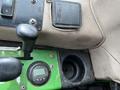 Close-up of the control panel of a 2014 John Deere 1585 Terrain Cut featuring levers and a digital display with a cup holder