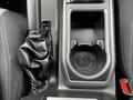 The interior console of a 2022 Toyota Tacoma featuring a gear shift covered in black leather and a cup holder with a textured bottom