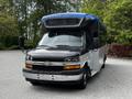 2019 Chevrolet Express with a black and white body and a blue roof parked with a front view showcasing its large windshield and side mirror