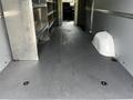 Interior view of a 2023 Mercedes-Benz Sprinter van featuring metal shelving units and a spacious cargo area with a flat rubberized floor