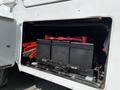 A compartment containing three black battery boxes secured with metal brackets and red wires visible on top