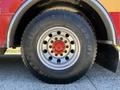 Close-up of a large tire from a 2004 American LaFrance Eagle with visible tread pattern and shiny chrome wheel rim featuring a red center cap