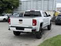 A white 2017 Chevrolet Silverado 1500 pickup truck viewed from the rear with a black bed cover and black wheels