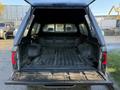 A 2004 Toyota Tacoma truck bed with a black camper shell, featuring a textured floor and side panels, empty and without any cargo