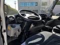 The interior of a 2020 Hino 155 featuring a steering wheel dashboard and gear shift with a simple and functional design