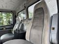 Interior of a 1998 Freightliner FL80 featuring two gray cloth seats and a black storage box between them