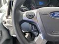 Close-up of a 2019 Ford Transit steering wheel featuring controls for audio and cruise settings with the Ford logo prominent on the wheel