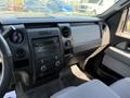 Interior view of a 2014 Ford F-150 featuring a black dashboard with audio controls a console and gray fabric seats