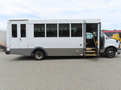 A 2020 Chevrolet Express bus with a white exterior and gray lower portion featuring large windows and an open door on the side