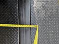 A measuring tape placed on a textured black floor surface next to a section of the 2015 Freightliner M2 106 showing measurement details