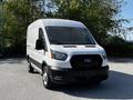 A white 2021 Ford Transit van with a black grille and clear headlights parked on a paved surface
