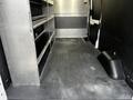 Interior of a 2021 Ford Transit van featuring metal shelving units along one side and a clean black rubber floor