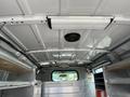 Interior view of a 2009 Ford Econoline van showing the ceiling with metal panels a light fixture and a speaker mounted above the driver’s seat area