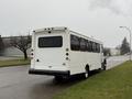 A white 2011 Ford F-550 bus with multiple windows parked on the side of a street