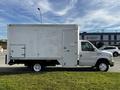 A white 2013 Ford Econoline cargo van with a large box-shaped cargo area and a side door