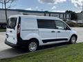 A white 2016 Ford Transit Connect parked on the side of the road with a sleek design and sliding side doors