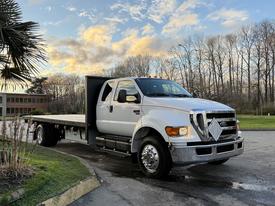 A white 2006 Ford F-650 flatbed truck with a large flatbed and dual rear wheels parked at an angle with the cab facing forward