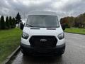 A white 2021 Ford Transit van with a prominent front grille and headlights facing directly towards the viewer