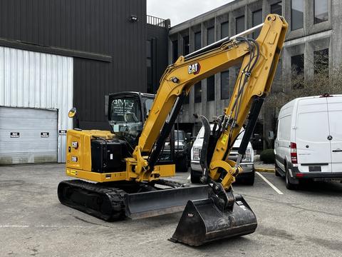 A yellow 2024 Caterpillar 306 excavator with a black bucket and tracks is positioned in a parking area