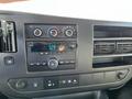 Black dashboard of a 2014 Chevrolet Express featuring a radio control panel with dials buttons and display showing the time and radio station