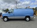 A blue 2009 Ford Econoline van with a silver stripe and a roof rack is parked on asphalt